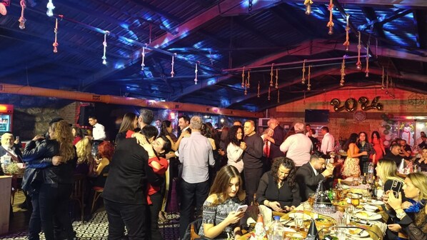 A crowded indoor event with people mingling and tables set up for dining. - Candarlı Çiftliği (Iznik)