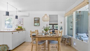 Uma cozinha espaçosa com uma mesa de jantar de madeira, cadeiras e luminárias pendentes.