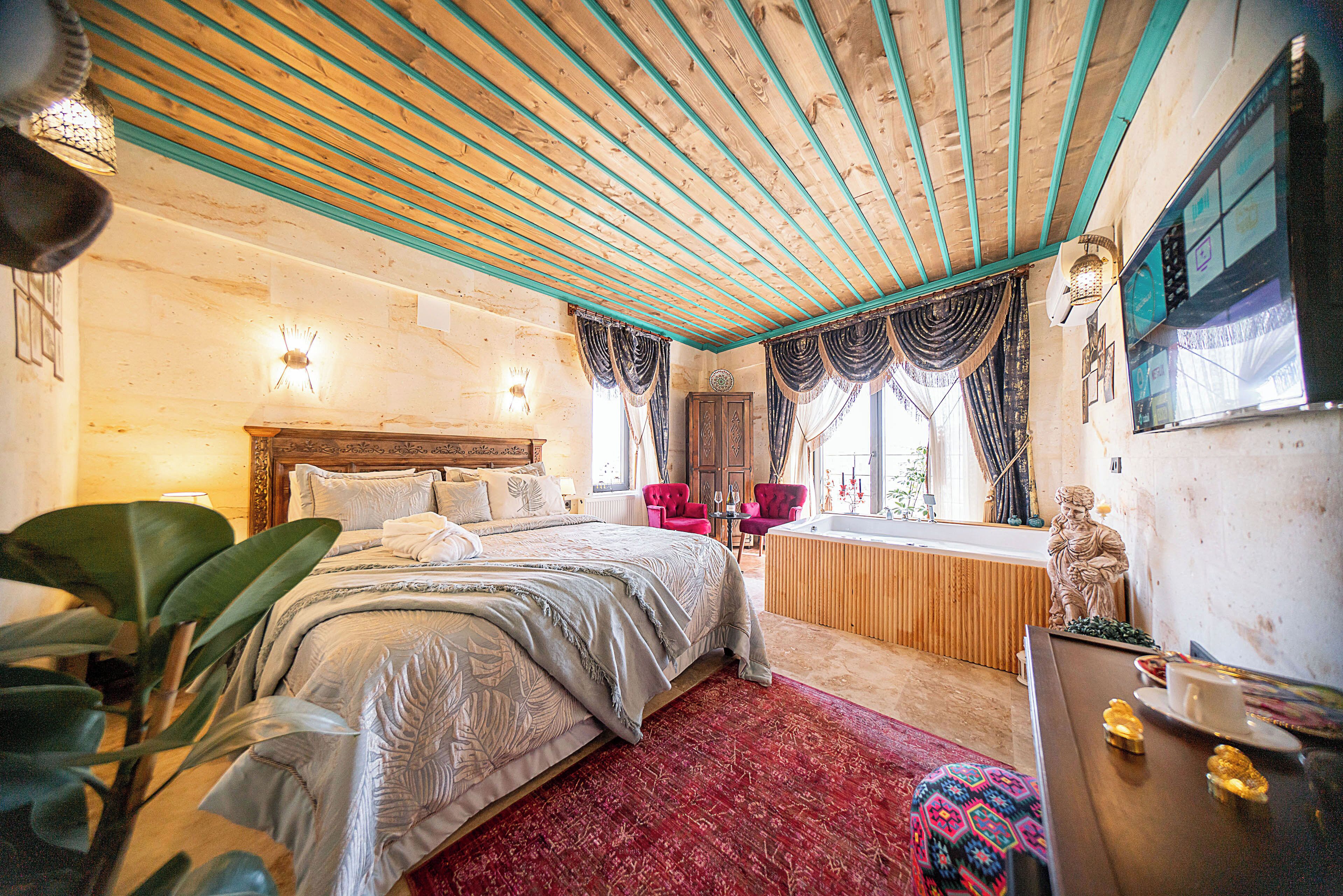 Un dormitorio con una cama grande, techo de madera, alfombra roja y una bañera.