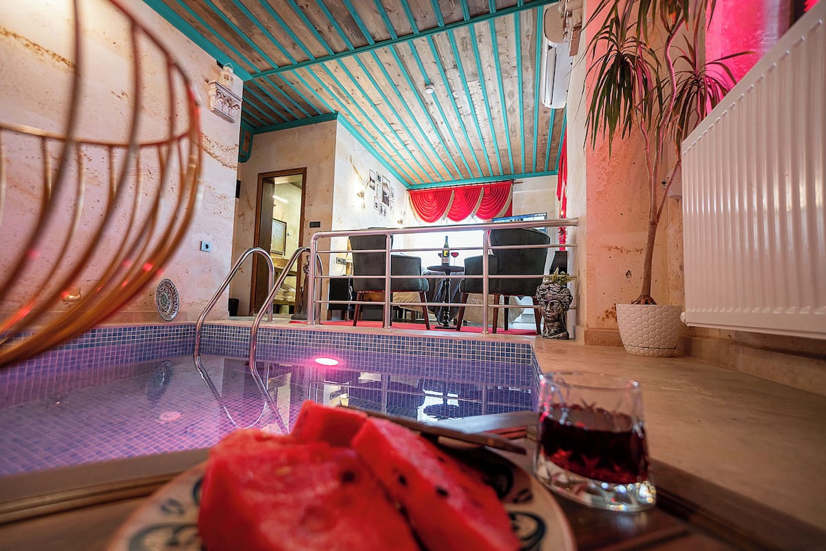 A room with a pool, a dining area, and a potted plant.