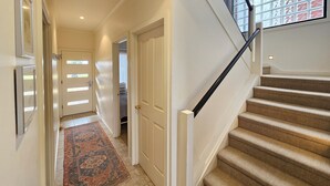 Un pasillo que conduce a una escalera con un tapete estampado y una puerta.
