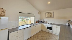 Una cocina moderna con armarios blancos, lavavajillas, estufa y microondas.