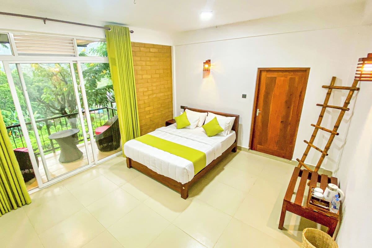 A bedroom with a bed, a wooden ladder, a door, and a balcony with a table and chairs.