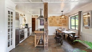 Eine moderne Küche mit weißen Schränken, einer zentralen Kochinsel und einem Essbereich mit Holztisch und Bänken.