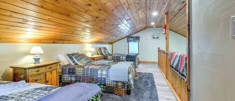 Un dormitorio con tres camas, techo de madera y una ventana.