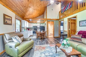 A spacious living room with a high ceiling and wooden beams, a dining area with a table and chairs, and a kitchen in the background. - Inviting Peru Cabin w/ Patio, Grill & River Access (Peru)