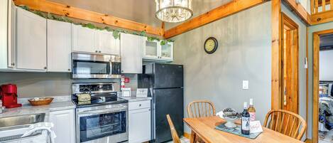 A kitchen with stainless steel appliances, a wooden dining table, and a chandelier.