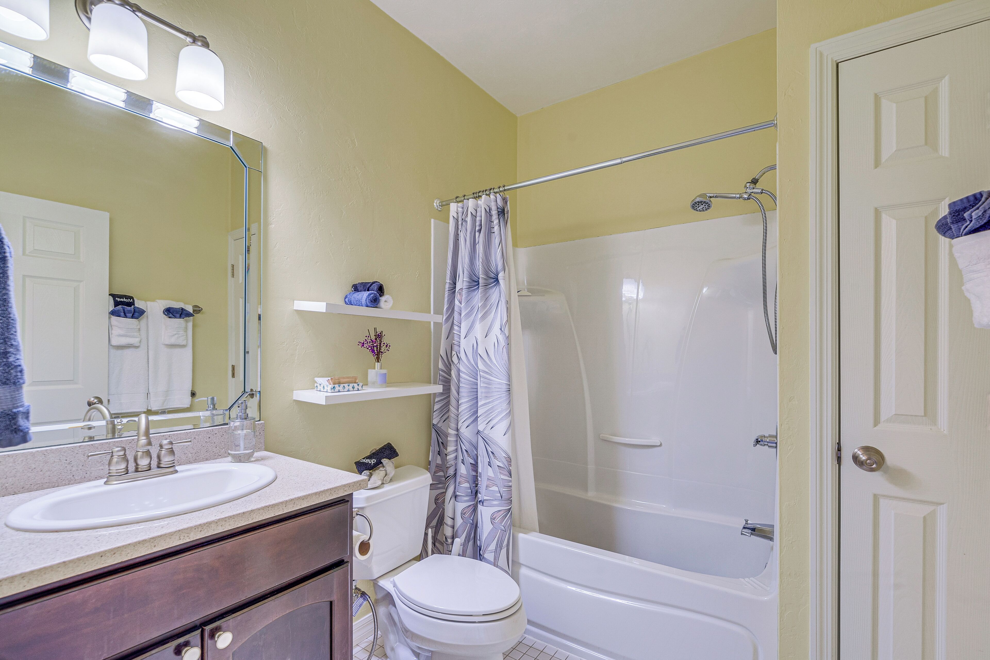 A bathroom with a white sink, toilet, and bathtub. There is a shower curtain and a mirror above the sink.