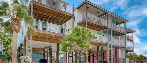 A multi-story residential building with balconies, a covered parking area, and a brick pathway.