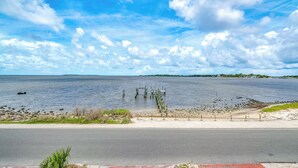 A waterfront view with a road, a dock, and a distant shoreline. - Steps to Beach: Waterfront Cedar Key Home! (Cedar Key)