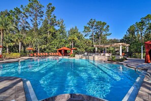 Une piscine à l’eau d’un bleu cristallin, entourée de chaises longues et agrémentée d’un belvédère.