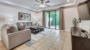 A spacious living room with a sofa, coffee table, and a ceiling fan.
