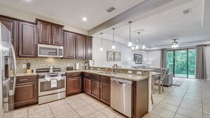 A modern kitchen with dark wood cabinets, stainless steel appliances, and a large island.