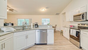 A modern kitchen with white cabinets, a dishwasher, a microwave, and an oven. - Crystal River Home w/ Lanai + Hot Tub (Crystal River)