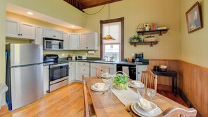A kitchen with wooden cabinets, a stainless steel refrigerator, a microwave, and a dining table set for four. - Restored Ovid Church Near Cayuga Lake Wine Trail (Ovid)