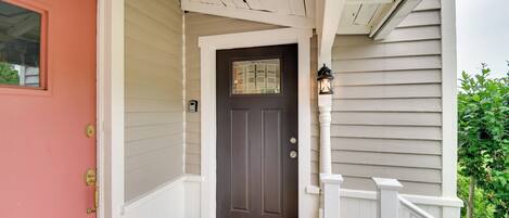 A front porch with a dark brown door, a welcome mat, and a small potted plant.