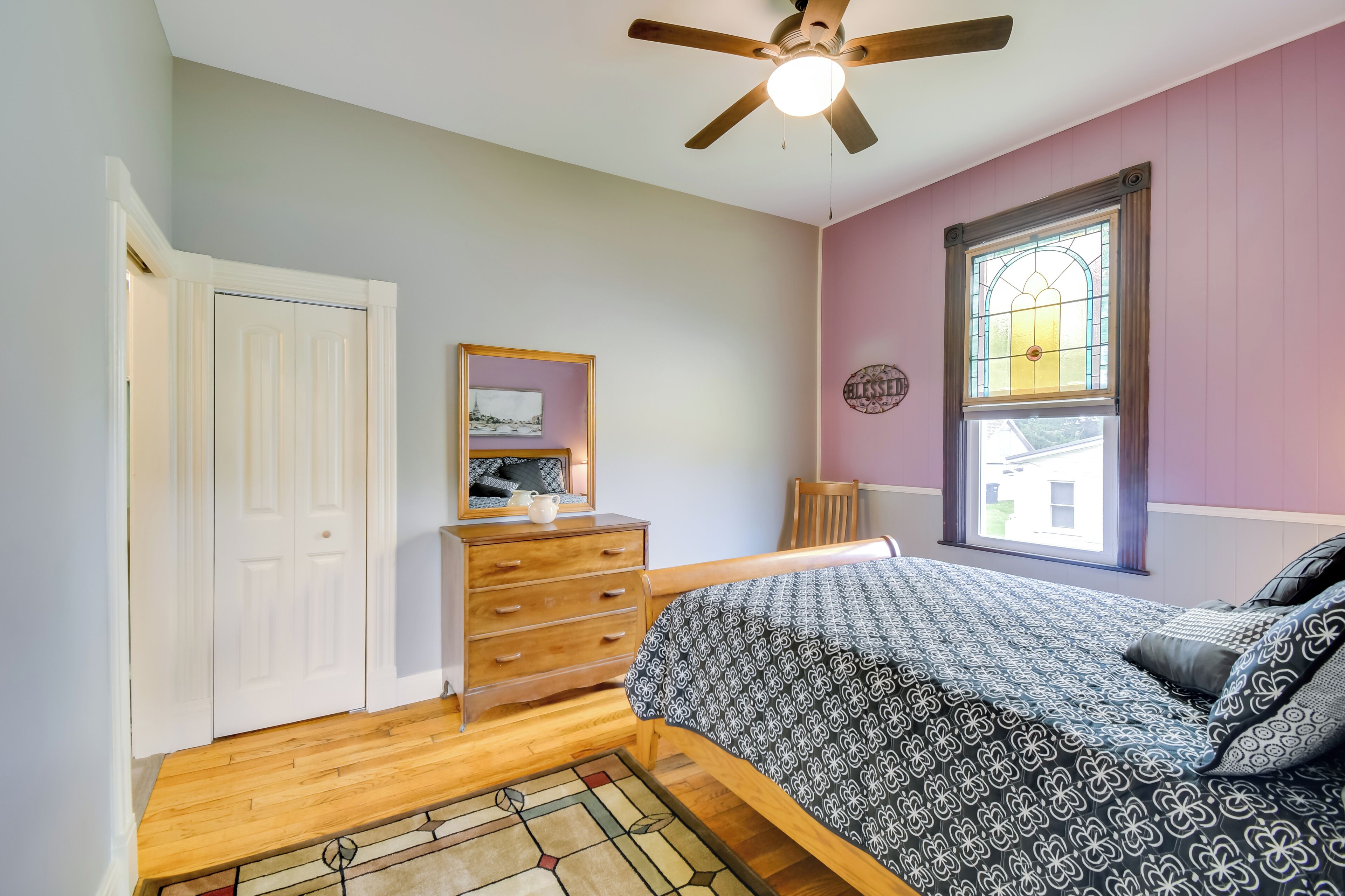 Une chambre à coucher avec un lit, une commode et un ventilateur de plafond.