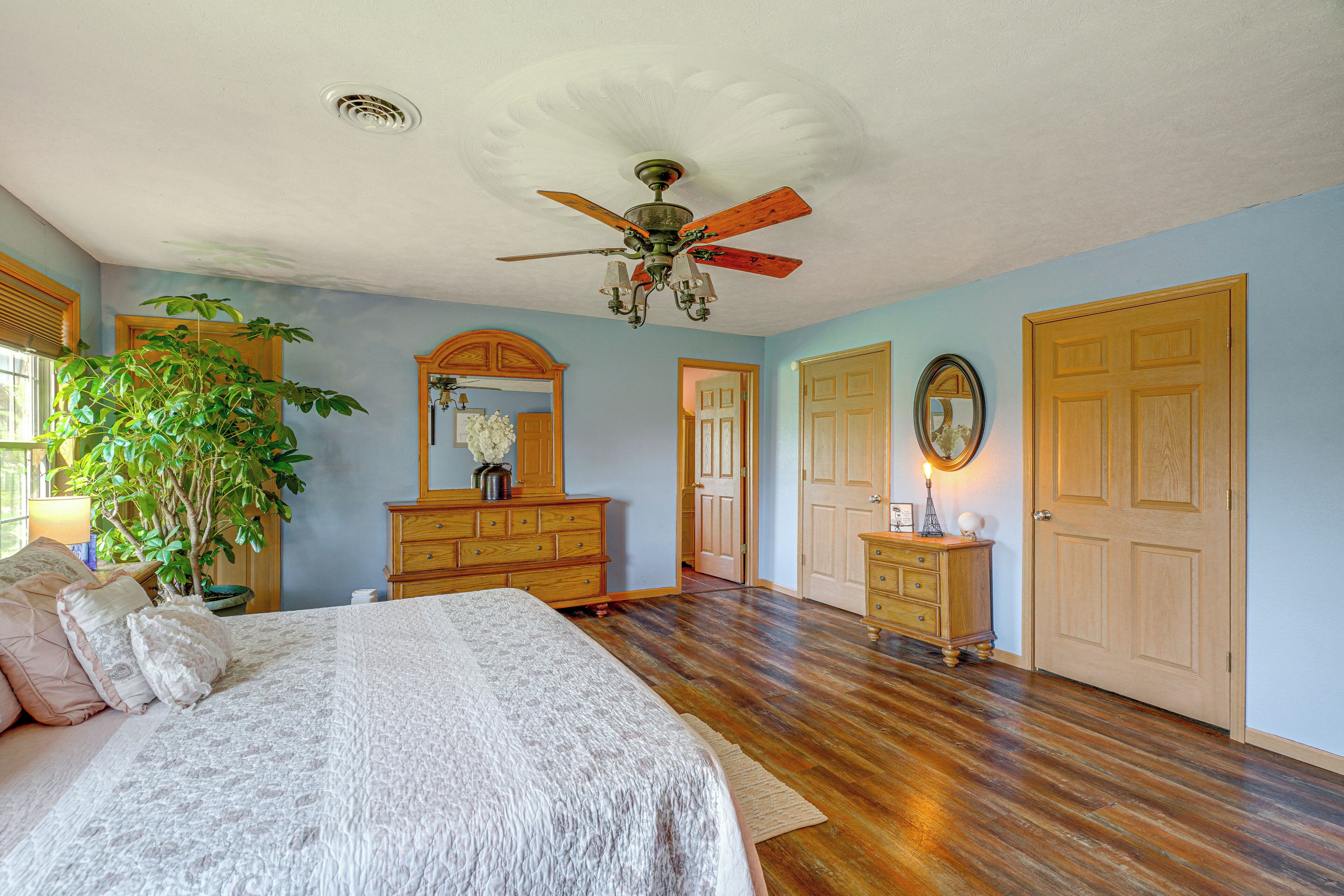 A bedroom with a bed, dresser, and a ceiling fan.
