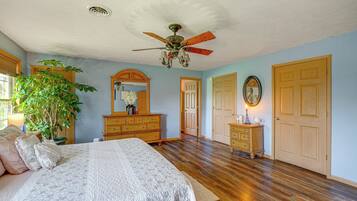 A bedroom with a bed, dresser, and a ceiling fan.