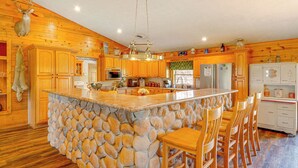 Una cucina con mobili in legno, un'isola in pietra e una testa di cervo appesa.