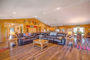 Relax in this inviting living room with a large sofa, dining area, and wooden decor.