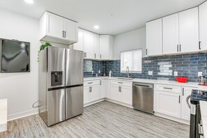 A modern kitchen with white cabinets, stainless steel appliances, and a blue-tiled backsplash. - Baltimore Townhome w/ Private Rooftop Patio! (Baltimore)