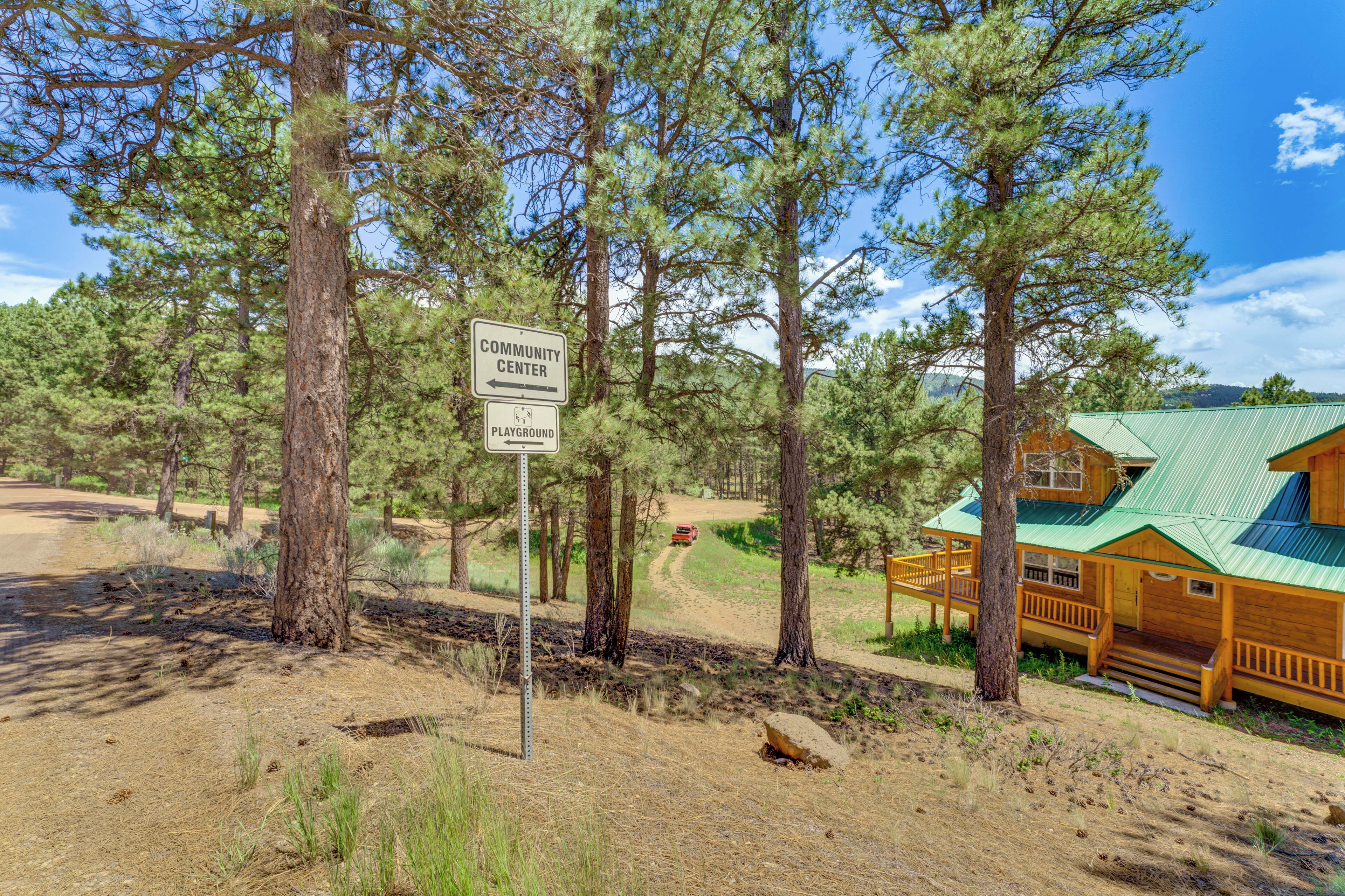 Eine Lodge mit Gründach, umgeben von Kiefern, mit Schild für Gemeinschaftszentrum und Spielplatz.