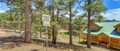 Eine Lodge mit Gründach, umgeben von Kiefern, mit Schild für Gemeinschaftszentrum und Spielplatz.