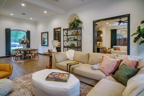 A spacious living room with a beige sofa, a coffee table, and a dining area with a wooden table and chairs. - Elegant Baton Rouge Home w/ Yard ~ 3 Mi to Lsu! (Baton Rouge)