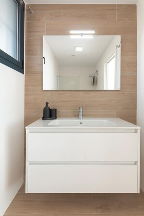 Une salle de bain moderne avec un meuble-lavabo blanc, un grand miroir et des carreaux de mur en bois.