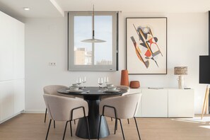 Un espace repas moderne avec une table ronde, quatre chaises et un luminaire suspendu.