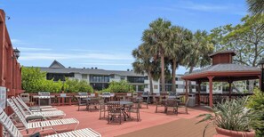 An outdoor patio with grilling stations, lounge chairs, and a gazebo.