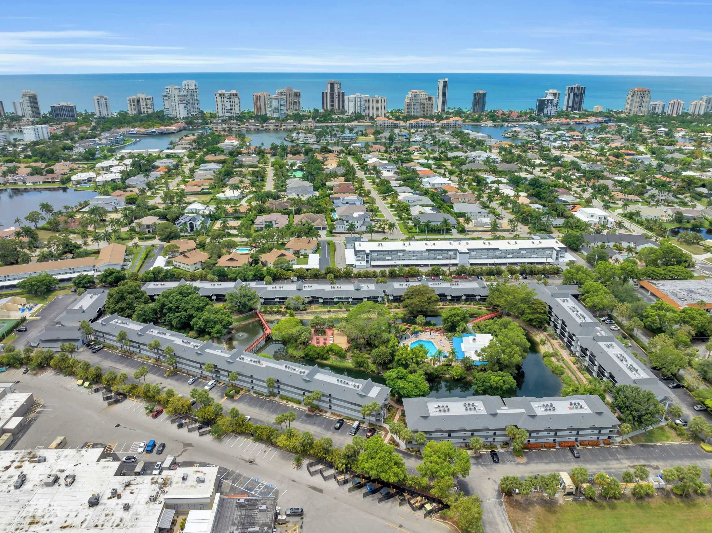 A residential area with a large building complex, a marina, and a view of the ocean.