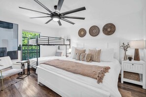 A modern bedroom with a large bed, a ceiling fan, and a view of greenery outside. - I-353 - Designer Furnished and Views & Sleeps 6 (Naples)