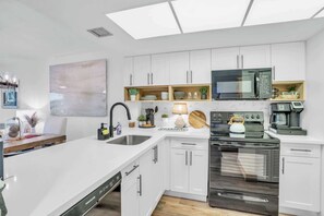 A modern kitchen with white cabinetry, a built-in microwave, a stove, and a dishwasher.