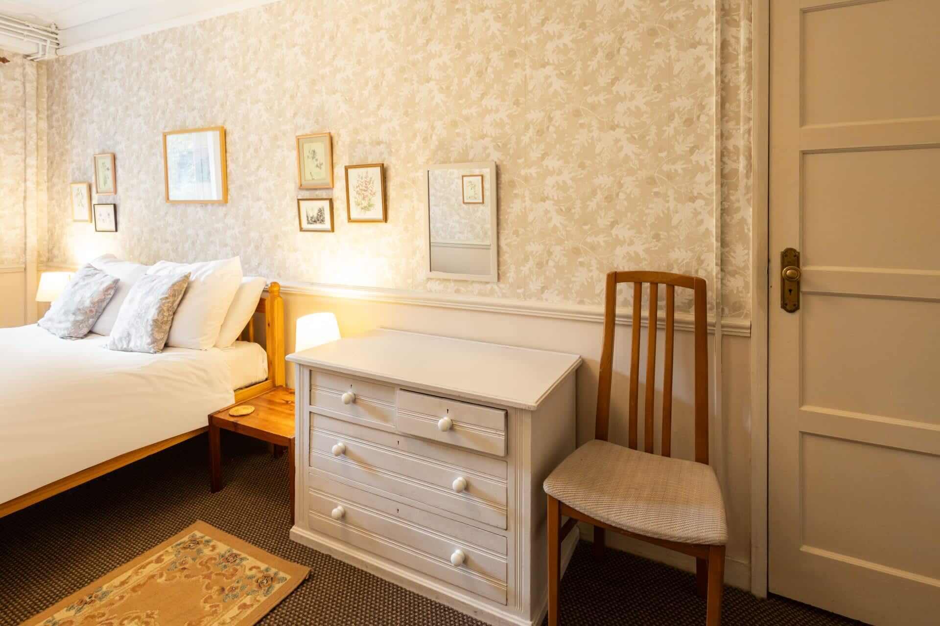 Une chambre à coucher avec un lit, une commode, une chaise et une porte.