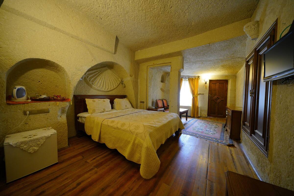 Un dormitorio con cama, piso de madera y una ventana pequeña.