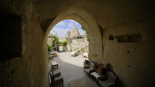 Cortile interno con pareti in pietra, posti a sedere all'aperto e vista su una vetta montuosa.