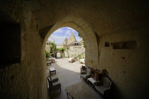 An interior courtyard with stone walls, outdoor seating, and a view of a mountain peak. - vezir cave suites (Nevsehir)