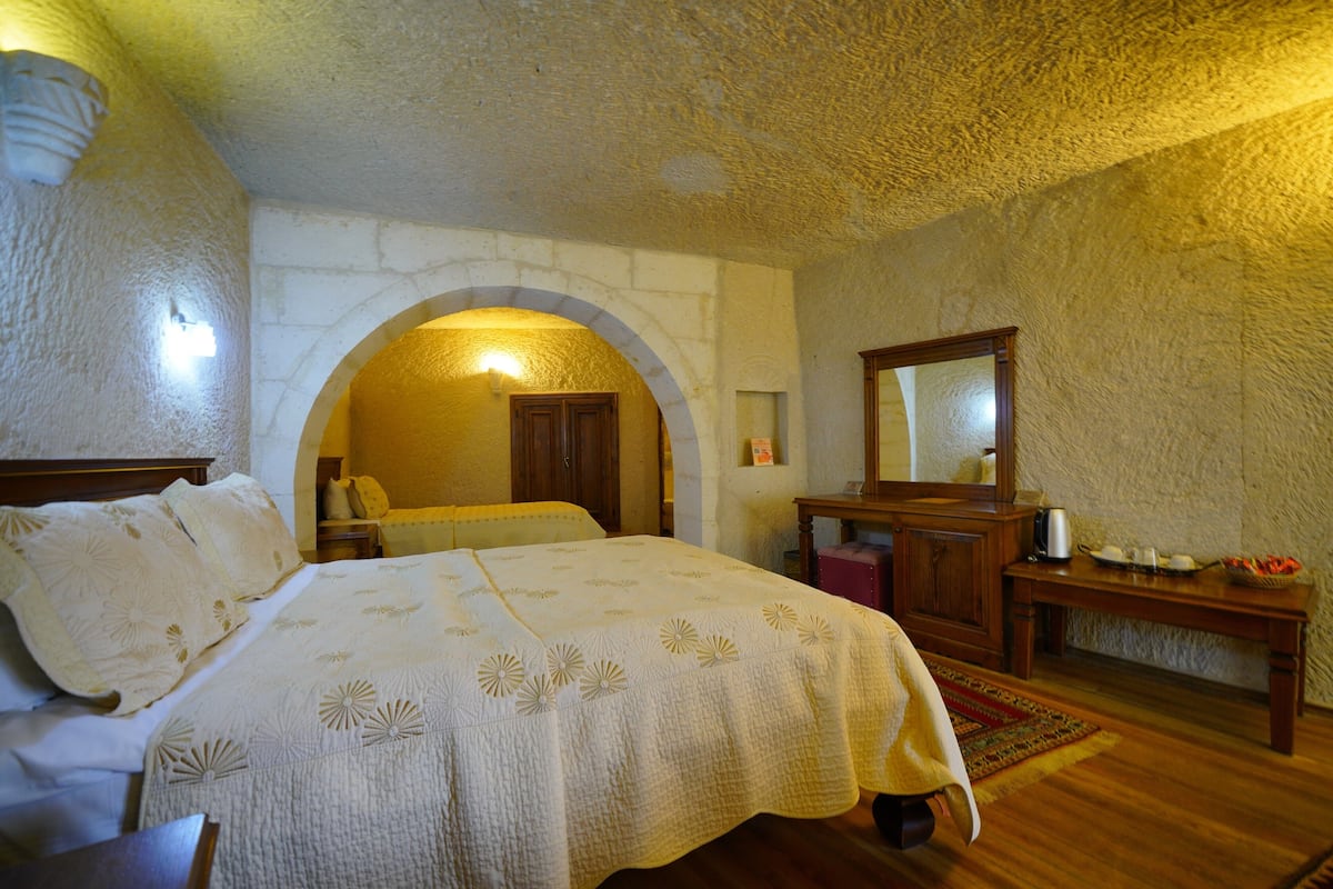 Un dormitorio con una cama grande, un arco de entrada, un aparador de madera y un espejo.