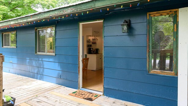 A blue house with a wooden deck, a door leading to a kitchen area, and a sign above the door reading "Cottage Tea Bar".