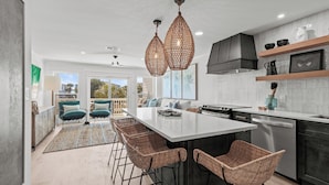 A modern kitchen with a central island, bar stools, pendant lighting, and a view to the outside. - Magnolia by the Sea, Priv Beach, Pool (Santa Rosa Beach)