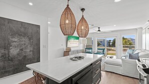 A modern kitchen with a large island, pendant lighting, and a view to the outdoors. - Magnolia by the Sea, Priv Beach, Pool (Santa Rosa Beach)