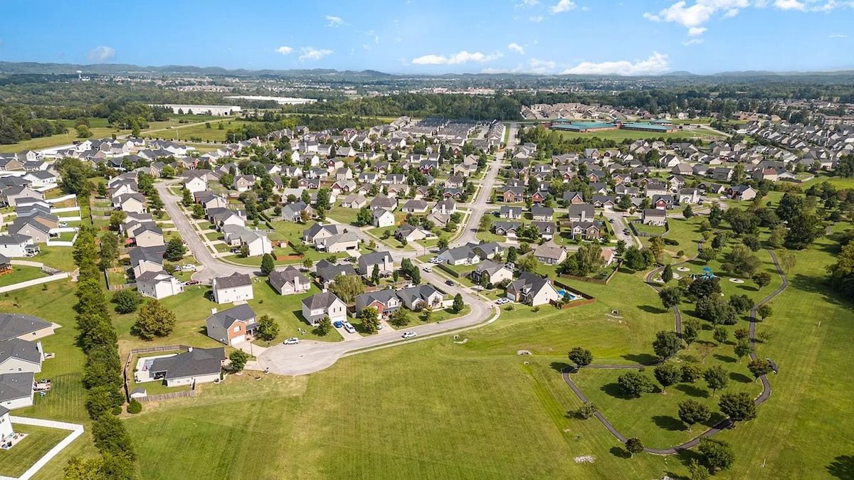 Vista aérea de una zona residencial con casas, calles y áreas verdes.