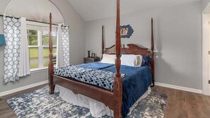 Una cama con dosel y un edredón azul, un plaid estampado y una almohada blanca.