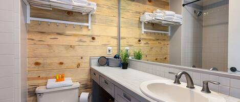 Un baño moderno con pared de madera, un espejo grande, un lavamanos y una ducha.