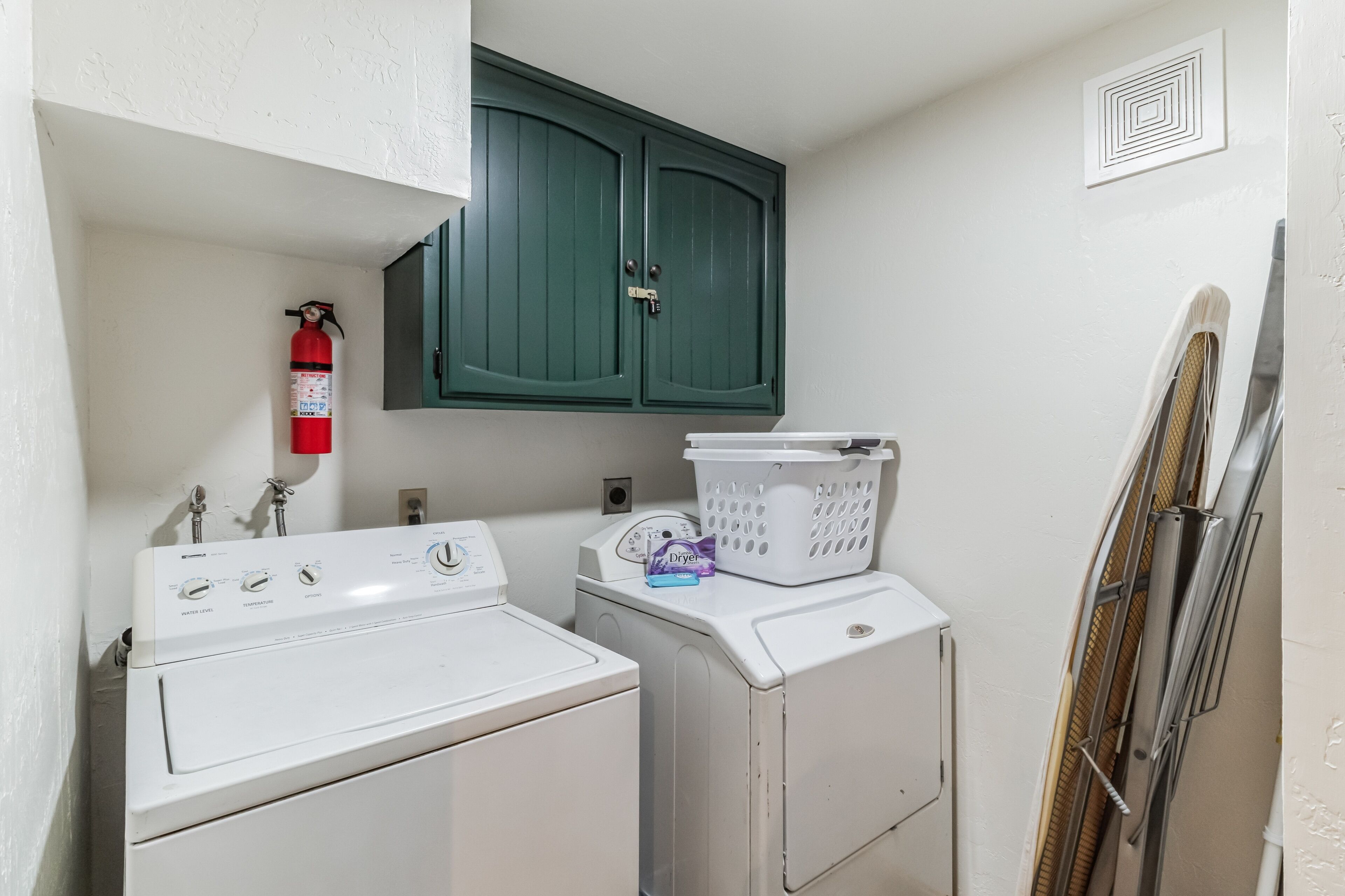 A laundry area with a washing machine, dryer, and a fire extinguisher on the wall.