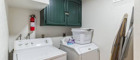 A laundry area with a washing machine, dryer, and a fire extinguisher on the wall.