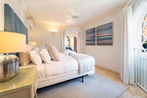A bedroom with a bed, bedside table, lamp, and artwork on the wall. - St. Peter's Bay 402 3 Bedroom Apts (Speightstown)