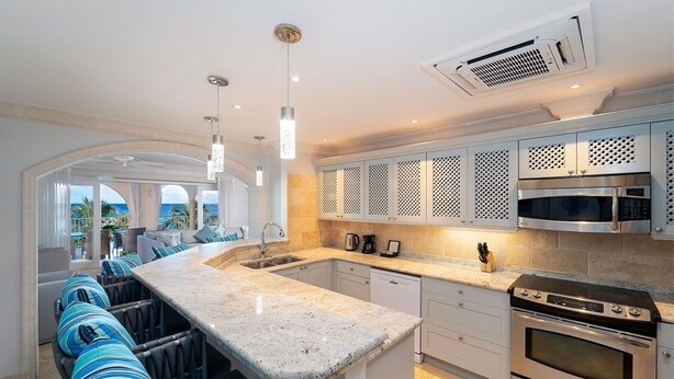 Una cocina moderna con una isla grande, electrodomésticos de acero inoxidable y vistas al exterior.